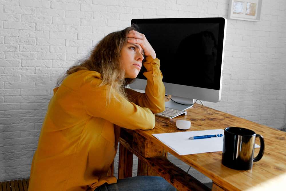 A woman designer sits in front of computer suffering from a creative block